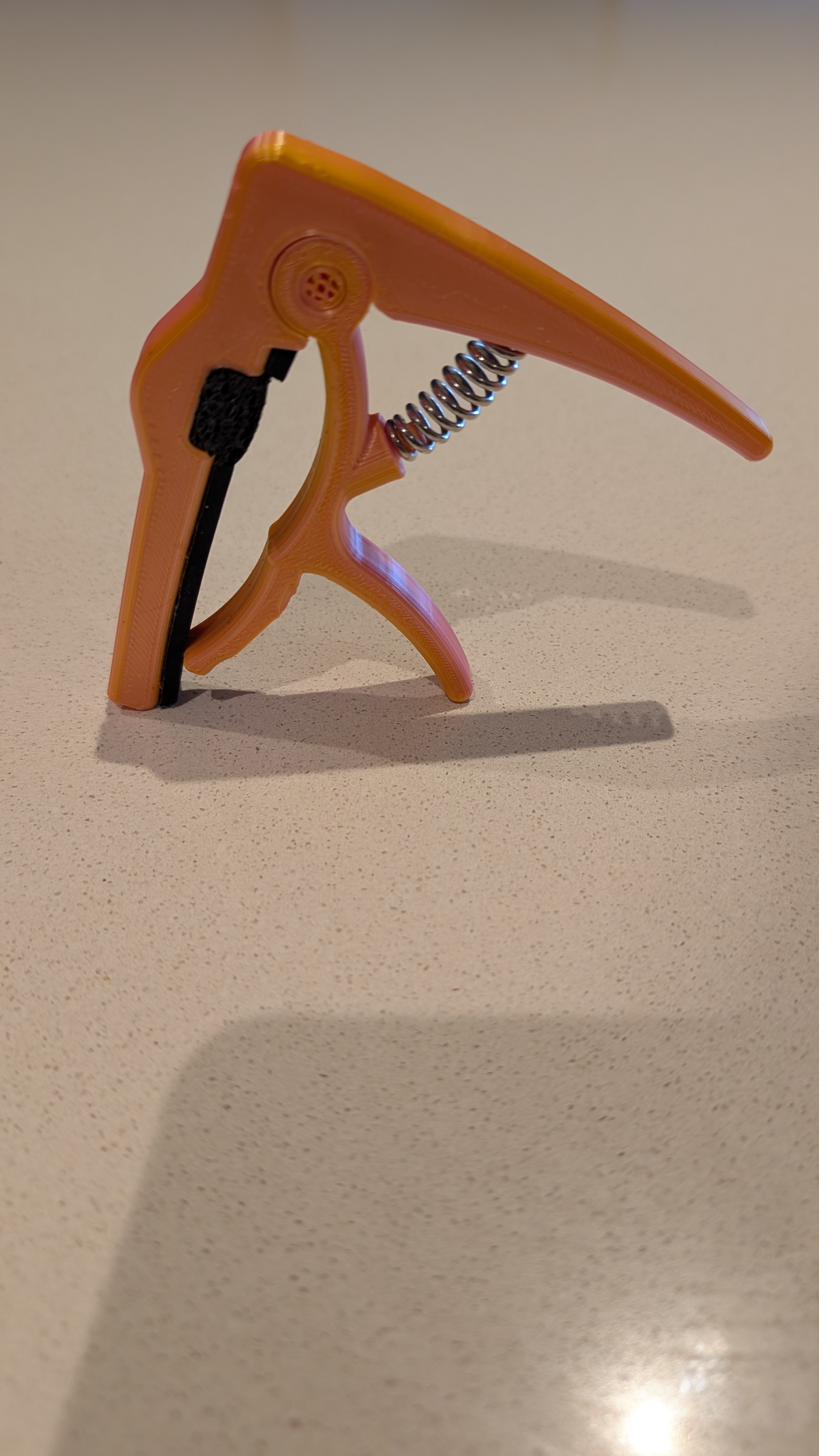 The Omega Capo prototype — a trigger capo with an extended upper arm and dampening pad